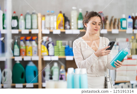 Woman client scans QR code on package and downloads promo code to purchase shampoo Woman client scans QR code on package and downloads promo code to purchase shampoo 125191314