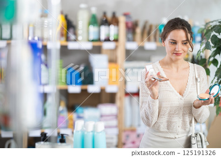 Young woman choosing eyeshadow and powder in store 125191326