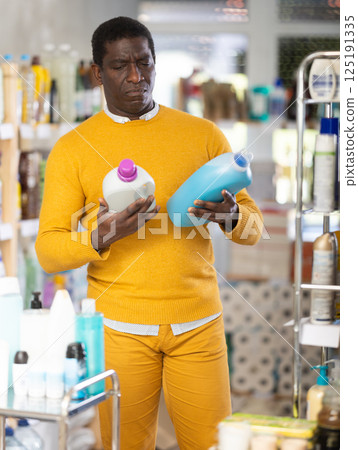 Male consumer with household chemical products for washing indoors Male consumer with household chemical products for washing indoors 125191335