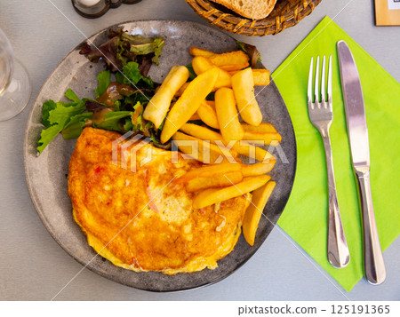 Omelet with lettuce and fries 125191365