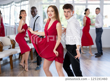 Group of young active people practicing vogue dancing movements while training twist or charleston in dance hall 125191460
