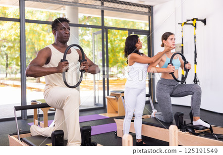 Healthcare professional helps an man restore health with gymnastic ring in pilates class 125191549