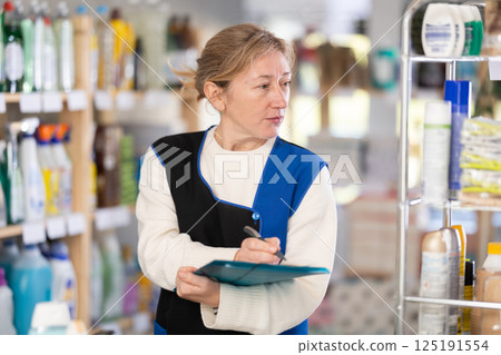 Adult woman seller conducting inventory in store 125191554