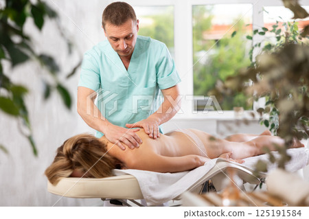The masseur makes a massage to woman 125191584