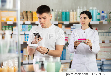 Attentive young guy choosing box of paracetamol antipyretic pills, scan QR code on label, positive young woman doctor helping 125191660