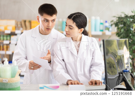 Two pharmacists employee using computer Two pharmacists employee using computer 125191668