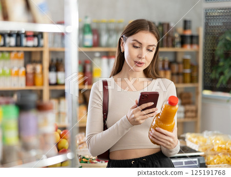 Young woman scanning qr code of peach juice 125191768