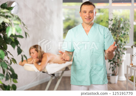 Male physiotherapist poses against background of spa salons office. Male physiotherapist poses against background of spa salons office. 125191770