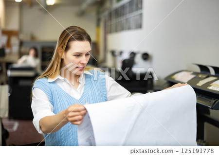 Worker in a printing and press centar check print quality Worker in a printing and press centar check print quality 125191778
