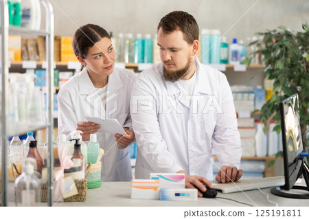 Two pharmacists working at a computer Two pharmacists working at a computer 125191811
