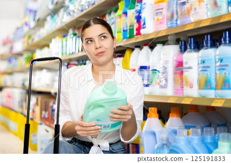 in store, girl carefully chooses household chemicals 125191833