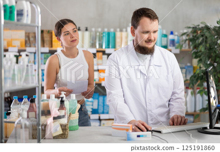Man pharmacist looking for prescription on computer for buyer Man pharmacist looking for prescription on computer for buyer 125191860
