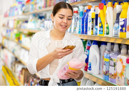Young woman looking up laundry detergent contents on internet in supermarket 125191880