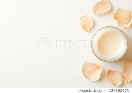 Top view of cream jar with rose petals on minimalist white background. Top view of cream jar with rose petals on minimalist white background. 125192075