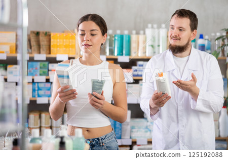Woman choosing cream with help from pharmacist 125192088
