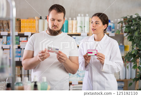 Man choosing paracetamol with help from pharmacist 125192110