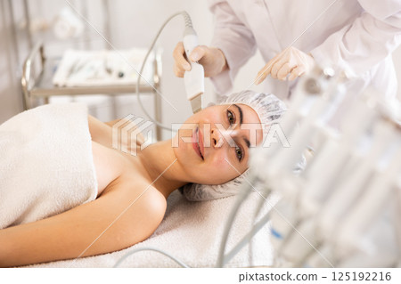 Young woman undergoing facial cleansing procedure using ultrasonic shovel Young woman undergoing facial cleansing procedure using ultrasonic shovel 125192216