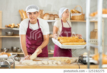 Male baker preparing raw yeast dough on kitchen table in bakery 125192275