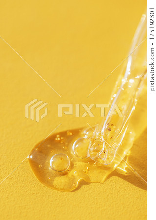 Cosmetic products. Vitamin essence with a dropper on a yellow background Cosmetic products. Vitamin essence with a dropper on a yellow background 125192301