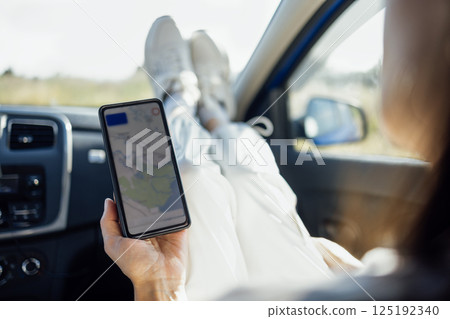 Close-up of a female face looking at the road on the navigator in the phone 125192340