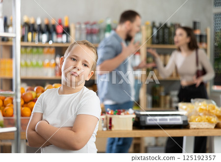 Portrait of capricious offended boy against the backdrop of arguing parents - family quarrel in grocery store 125192357