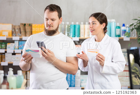 Man buyer scans pills qr code with woman pharmacist Man buyer scans pills qr code with woman pharmacist 125192363