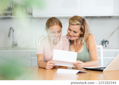 Joyful and overjoyed mother and teenager daughter reads letter and learn good news 125192544