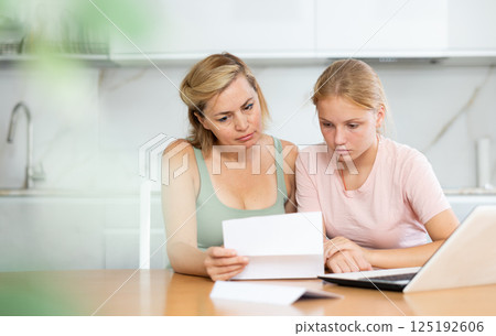 Upset and distressed mother and teenager daughter reads letter and learns unpleasant news Upset and distressed mother and teenager daughter reads letter and learns unpleasant news 125192606
