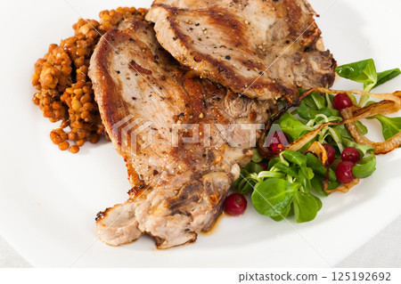 Roasted pork shin with lentils, greens and berries 125192692