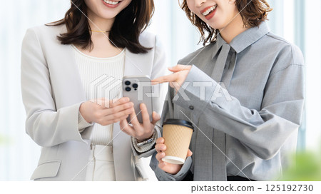 Two women/businesswomen looking at smartphones 125192730