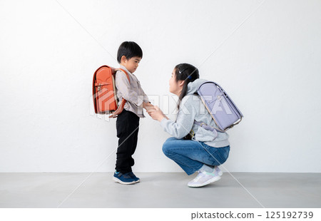 Siblings holding hands and carrying backpacks 125192739