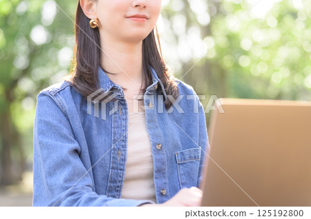 A young woman operating a computer at the park A young woman operating a computer at the park 125192800