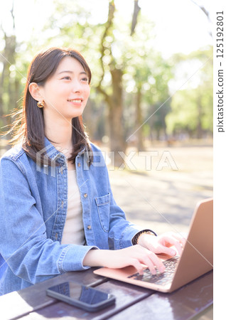 A young woman operating a computer at the park A young woman operating a computer at the park 125192801