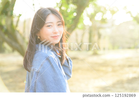 Young woman looking back in the sun Young woman looking back in the sun 125192869