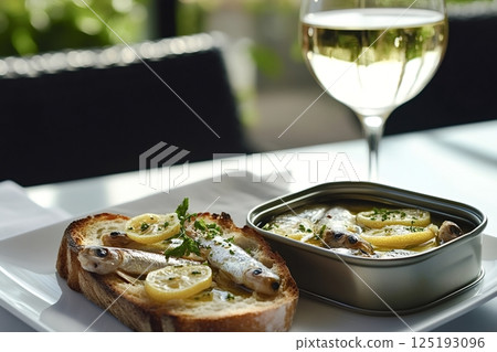 Sprats with lemon and parsley on toast with white wine 125193096