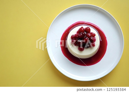 Delicious panna cotta with wild berries and berry sauce on yellow background 125193384