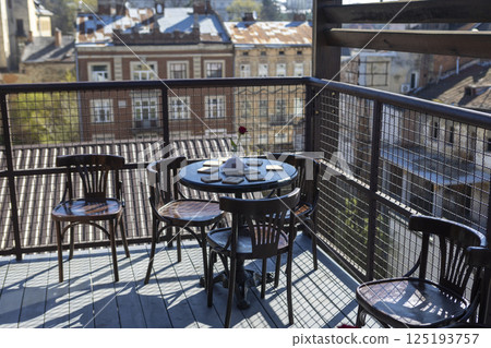 Terrace with table and chairs against the backdrop of a European city Terrace with table and chairs against the backdrop of a European city 125193757