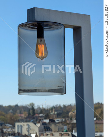 Modern lamp with glass shade against clear blue sky. 125193827