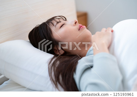 一個睡在床上的年輕女人 125193961