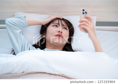 一個年輕女子舉著頭看著她的智能手機 125193964