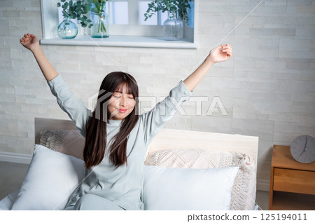 Young woman stretching in bed 125194011
