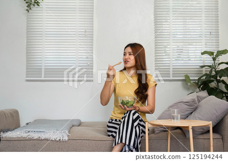 Morning Meal and Wellness. A woman enjoys her healthy salad, highlighting a positive morning routine. 125194244