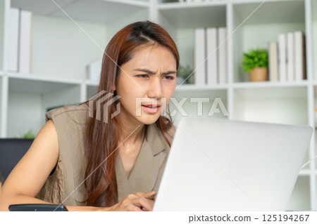 Focused Work and Data Evaluation. A woman intensely reviewing data on her laptop screen. Focused Work and Data Evaluation. A woman intensely reviewing data on her laptop screen. 125194267