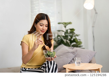 Healthy Breakfast and Nutrition. A woman enjoying a wholesome salad as part of her morning meal for a healthy start to the day. 125194286