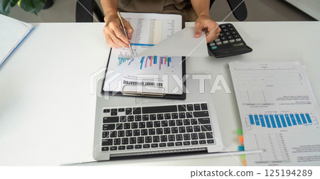 Financial Organization and Data Review. An individual sorting through financial reports and documentation on a desktop. Financial Organization and Data Review. An individual sorting through financial reports and documentation on a desktop. 125194289