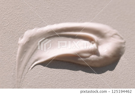 Close-up of the texture of pink cream on a light background. Moisturizing serum is smeared on the backdrop. The consistency of glycerin gel. Cosmetic smear. 125194462