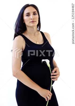 Portrait of an attractive young pregnant woman in a black dress with a flower Portrait of an attractive young pregnant woman in a black dress with a flower 125194467