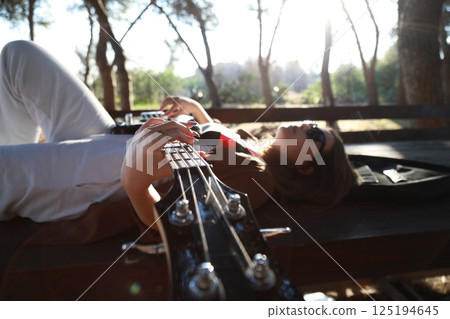 Girl Plays Bass Musical Instrument Lying On Table In Mountains 125194645