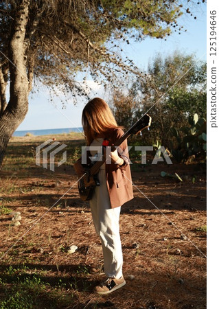 Girl With Sunglasses Plays Bass Musical Instrument In The Countryside Among Tree 125194646