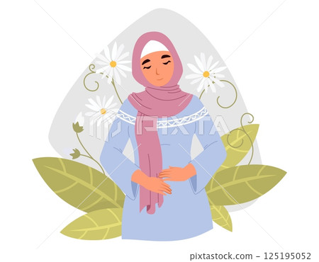 A woman dressed in a blue traditional dress and a pink scarf smiles gently while holding her hands on her stomach 125195052